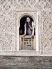 Zwei Frauen schauen aus einer reich verzierten Fensterffnung in der Medersa Ben Youssef in Marrakesch, Marokko
